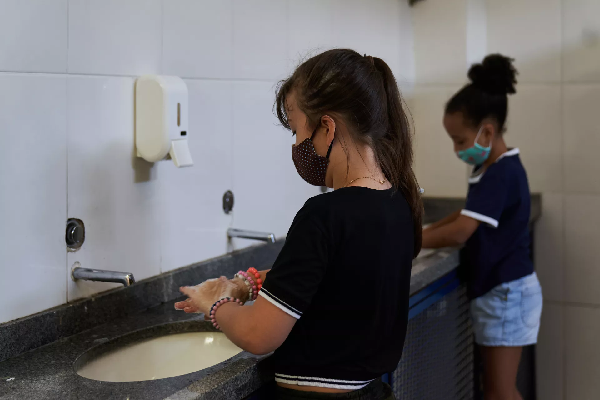 Crianças usando máscaras e lavando as mãos corretamente, destacando a importância da higiene na prevenção de doenças respiratórias como o HMPV.